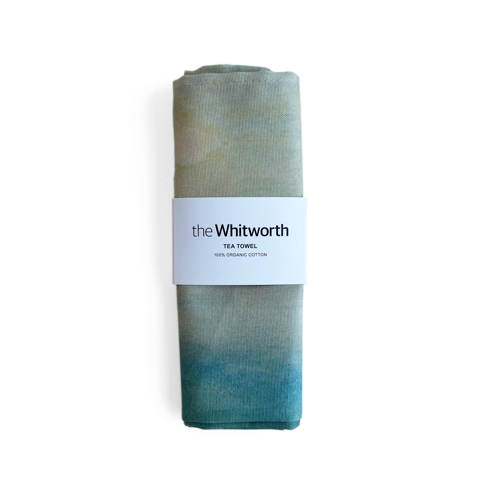 Tea towel folded up with a belly band with the Whitworth logo on it.