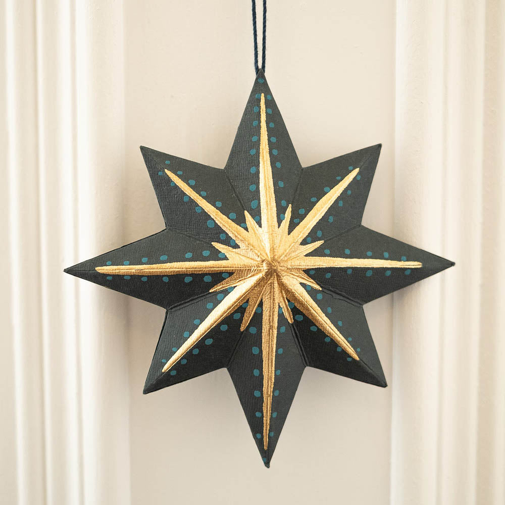 Decorative star ornament with gold and black design on a neutral background
