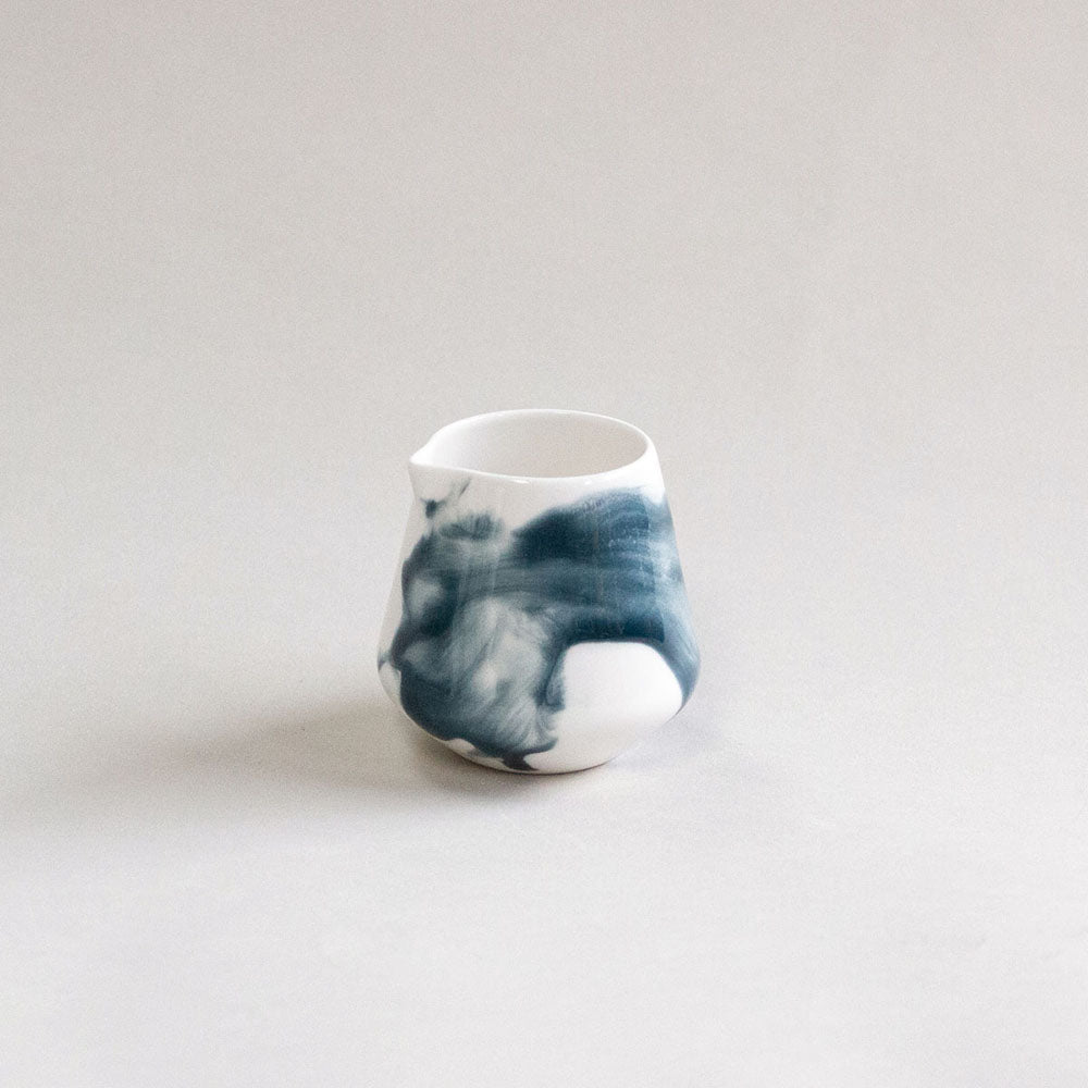 White ceramic jug with blue wash pattern photographed in front of a white background