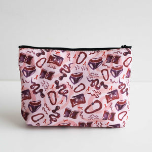 Cosmetics bag against white backdrop. Sarah-Joy Ford's A Queer Manifesto print. Pink, purple and red textile design