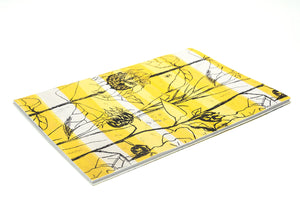 Image of a rectangular notebook taken from an angle, laid flat on its back, the cover is Althea McNishs textile design Van Gogh. White backdrop.