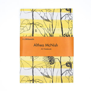 Image of a rectangular notebook, the cover is Althea McNishs textile design Van Gogh. White backdrop. Notebook has orange belly band with the Whitworth logo and words Althea McNish A5 notebook at the centre.