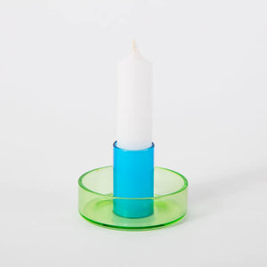 White background shot of the green and blue duo tone glass candle holder with a white candle in it.