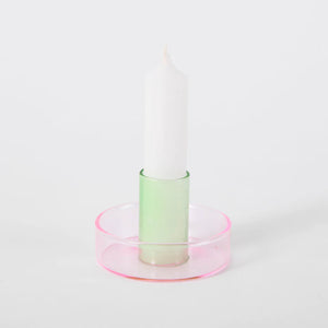 White background shot of the green and pink duo tone glass candle holder with a white candle in it.