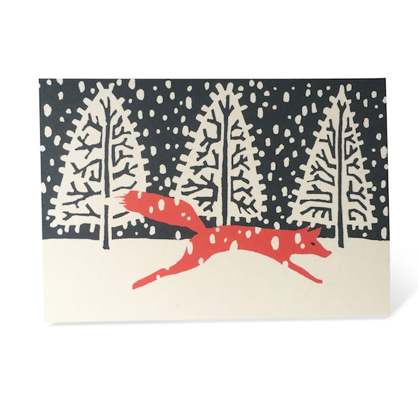 Christmas card of a fox in a winter scene with a red fox in front of trees.