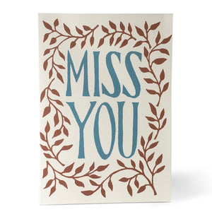 Cream Card with Miss You in blue font at the centre. Floral pattern around the outside.