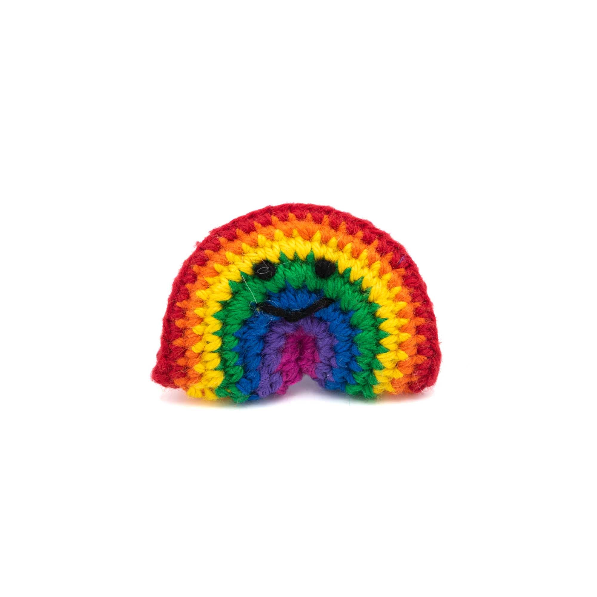 Crochet rainbow brooch with a little smiley face in black thread.