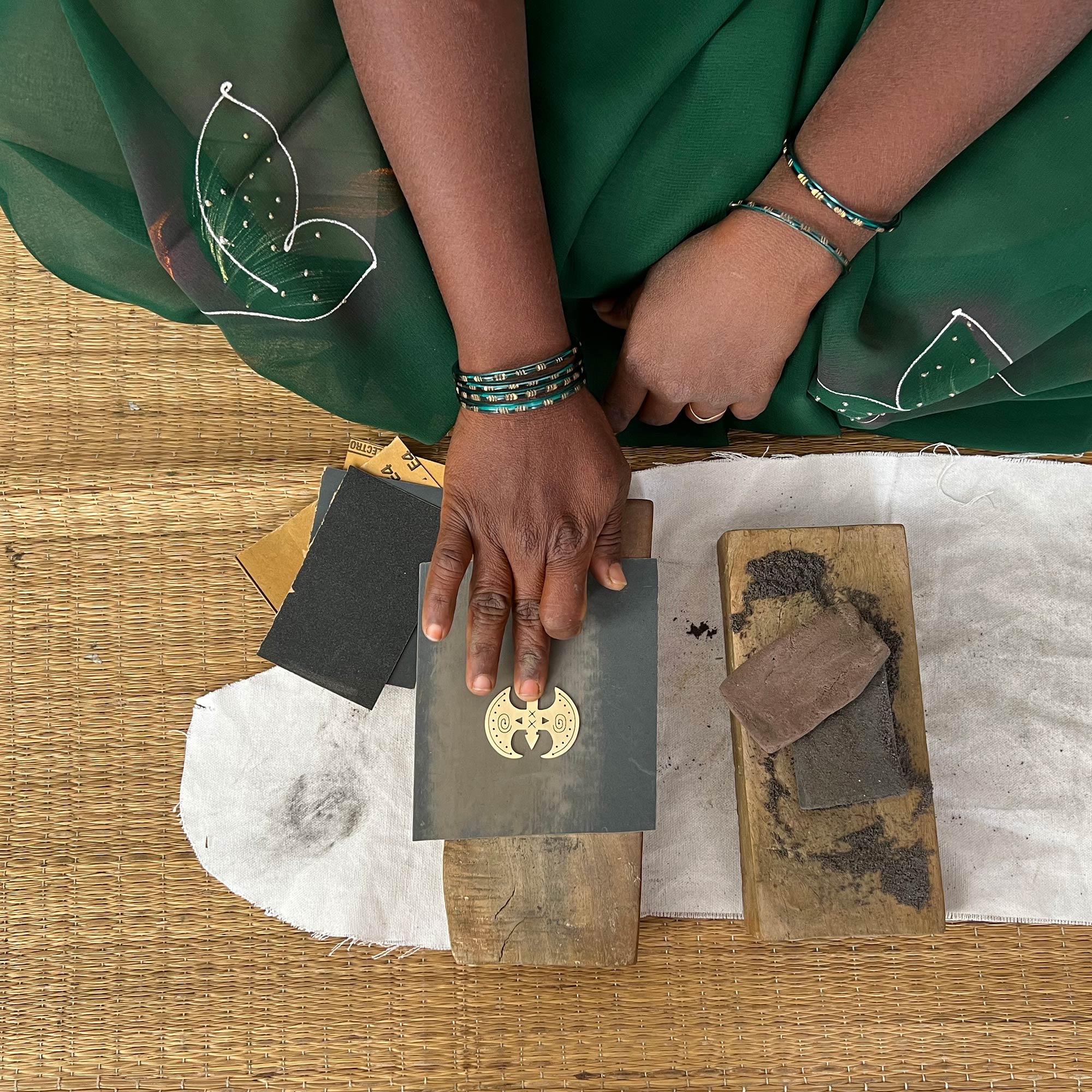 A woman sanding the Labrys pendant. Image cred Just Trade.