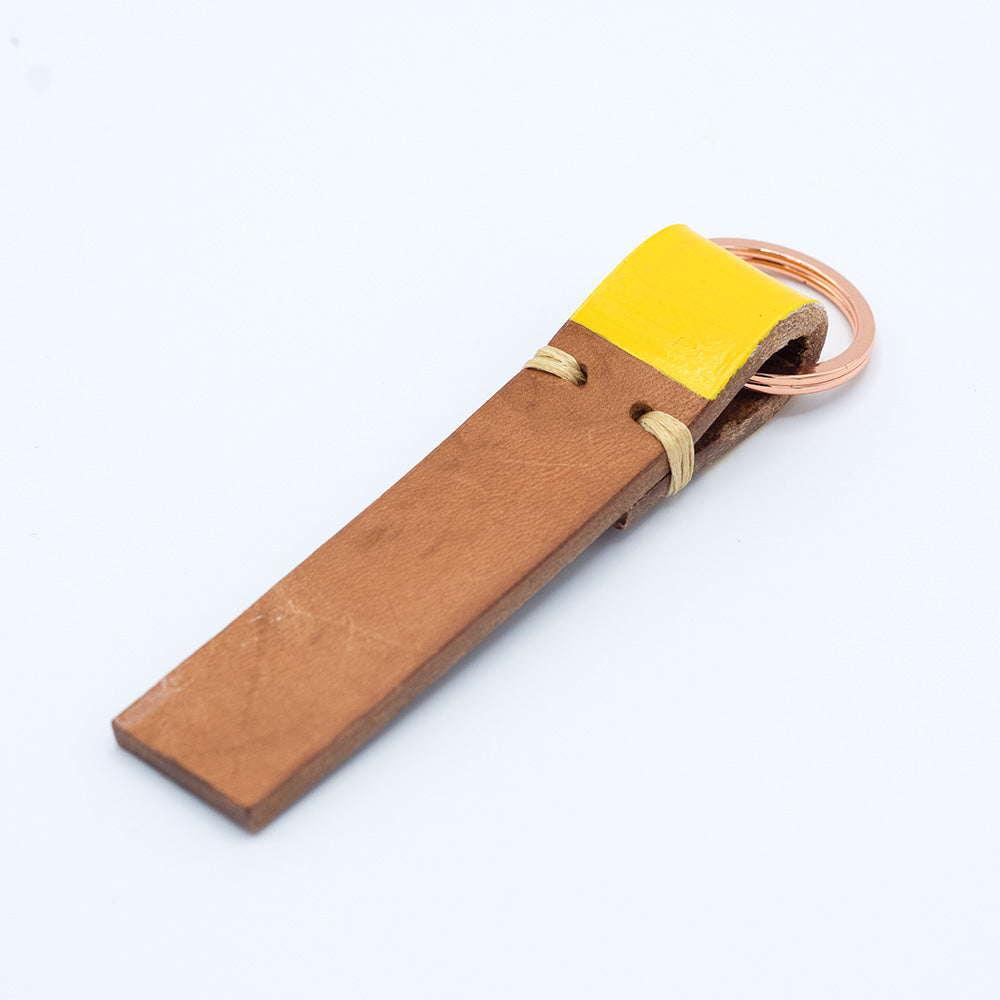 Image of brown leather keyring with yellow detail against a white background.