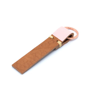 Image of brown leather keyring with pale pink detail against a white background.