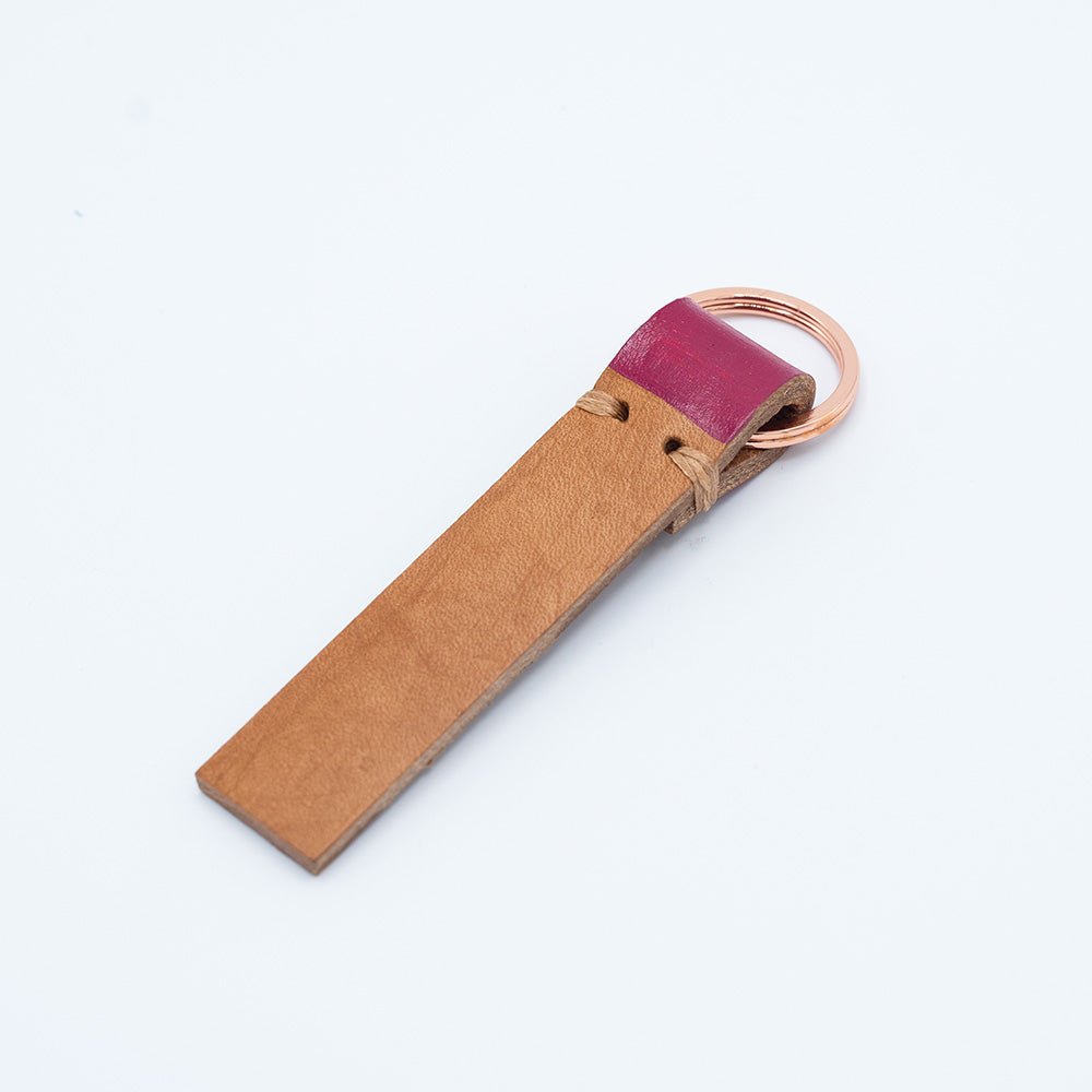 Image of brown leather keyring with pink detail against a white background.