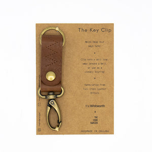 Image of a brown key clip on brown packaging against a white background.