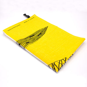 Image of tea towel folded in to 1/4. Yellow design with black leaf detail. Text reading 'twentytwentyone, made in ireland'