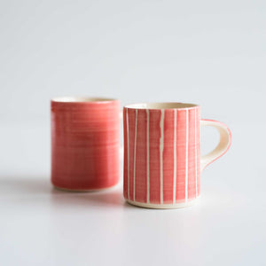 Two pink espresso cups. One striped and one plain