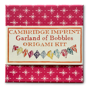 Box packaging of Cambridge Imprint Garland of Bobbles Origami Kit. The box is pink with white stars: belly band with branding surrounding the box.