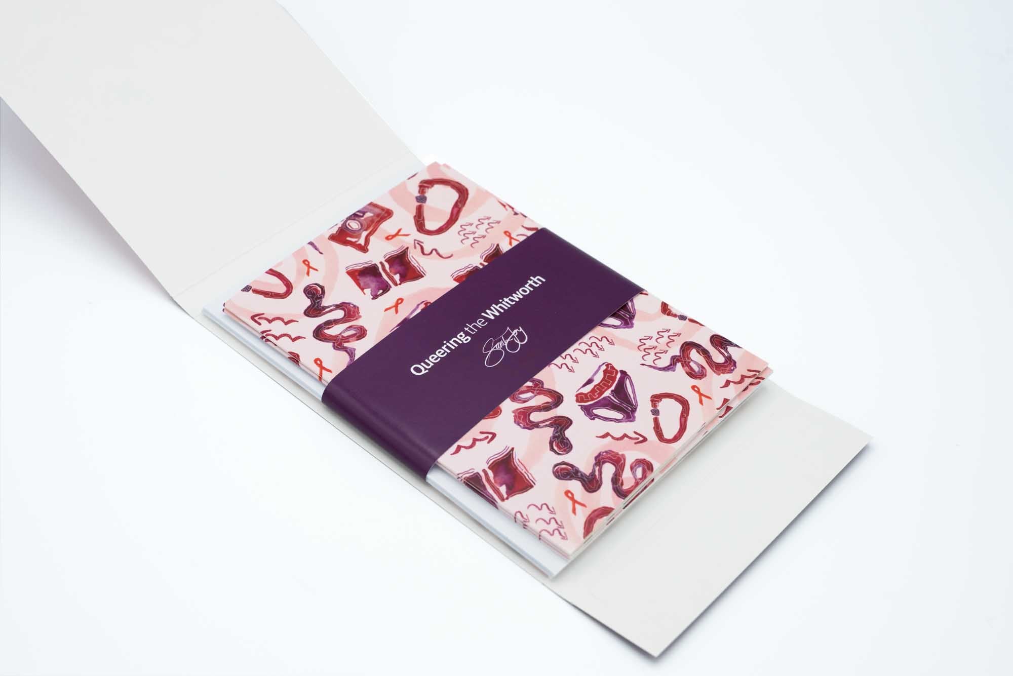 Inside of the greetings card set featuring the cards, envelopes and belly band with Queering the Whitworth branding. White background.