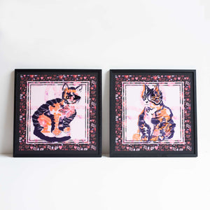 2 framed embroideries of cats. Placed side by side against an off-white background.