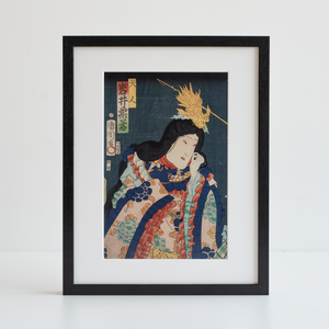 Japanese woodcut print in black frame photographed in front of a white background