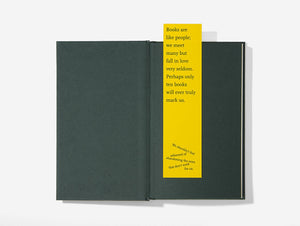 A yellow bookmark with black text laid on top of an insert of a book with black pages.