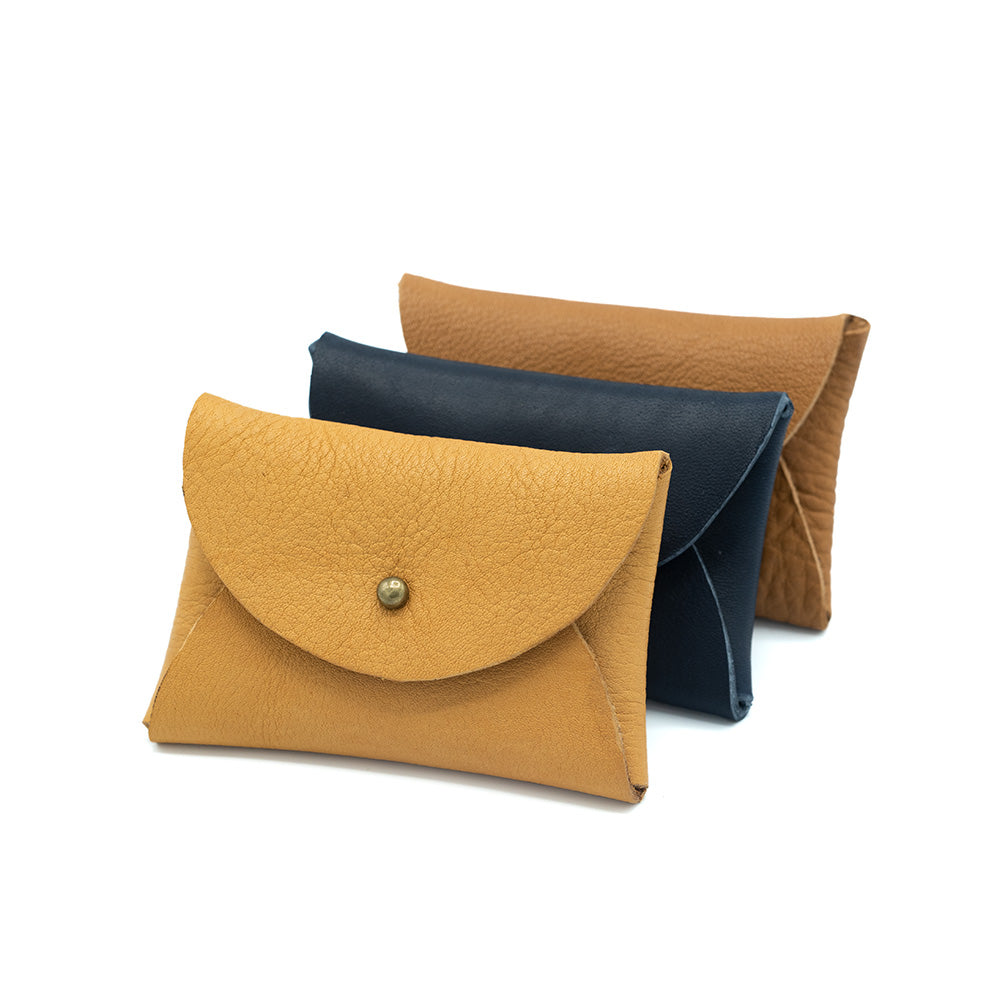 Image of three leather purses lined in front of each other. White backdrop.