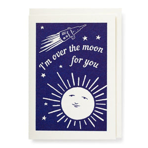 Card, cream envelope and blue print. There is a space rocket a shining moon with a face. Text reads Im over the moon for you.