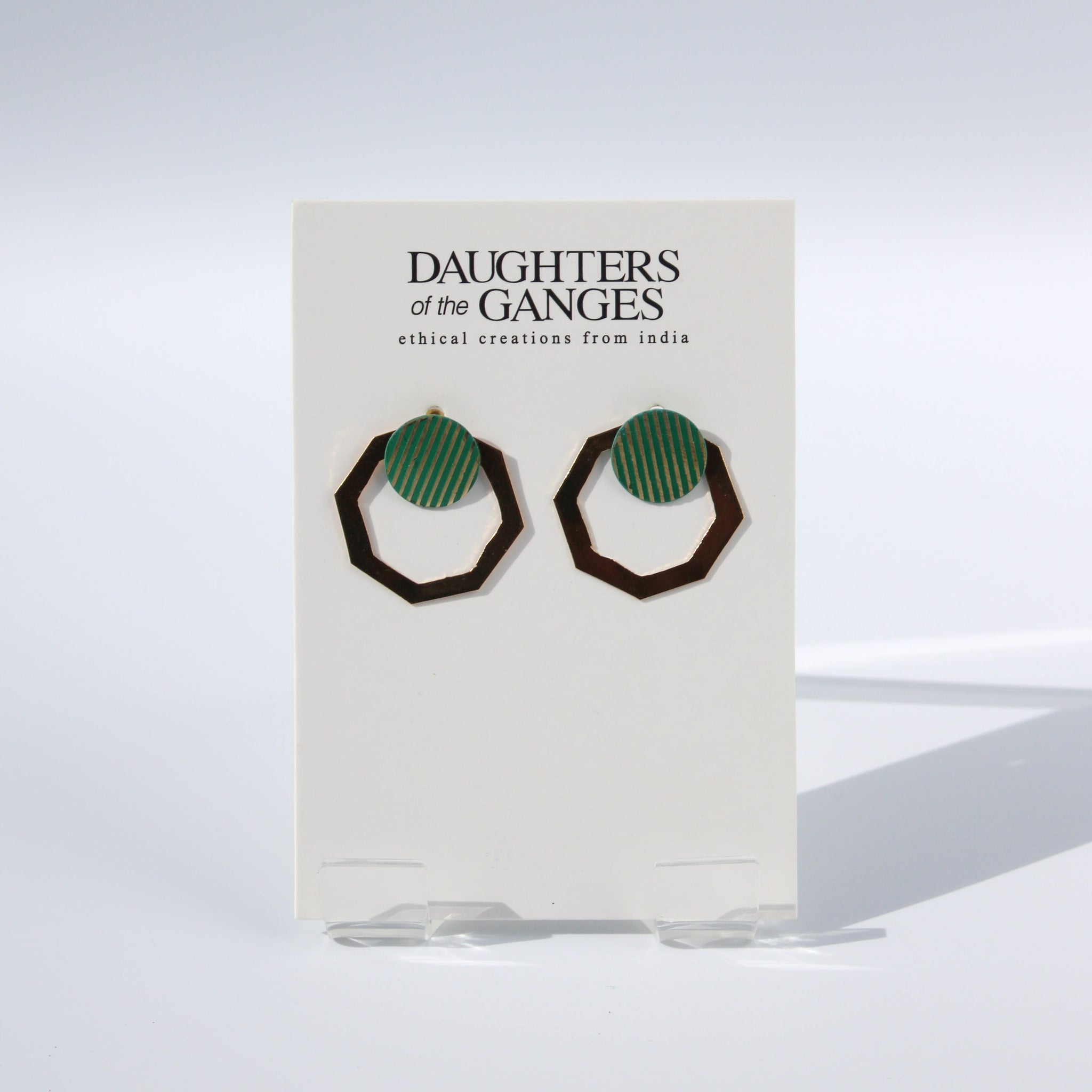 A pair of hexagonal brass earrings with a round disc at the fastening. The disc has copper green vertical lines over the brass.