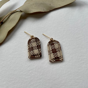Gingham earrings rested on a cream background