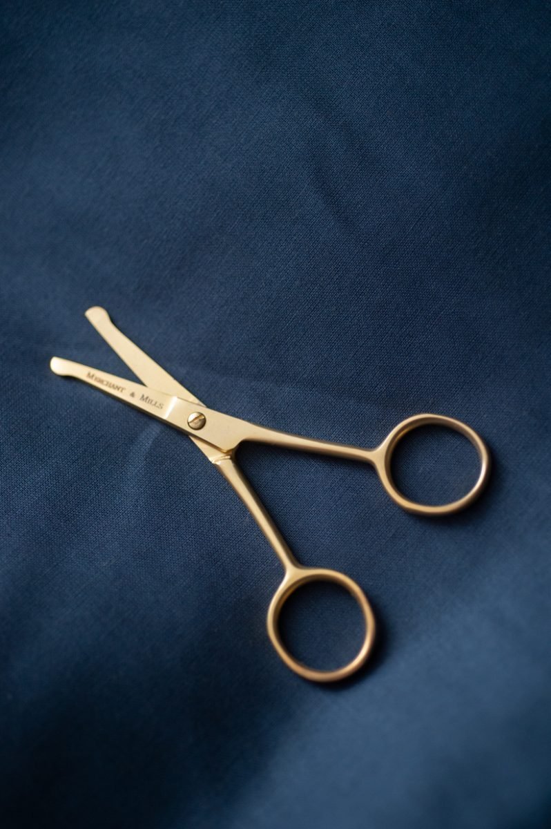 The gold scissors on a dark background, the scissors are slightly open.