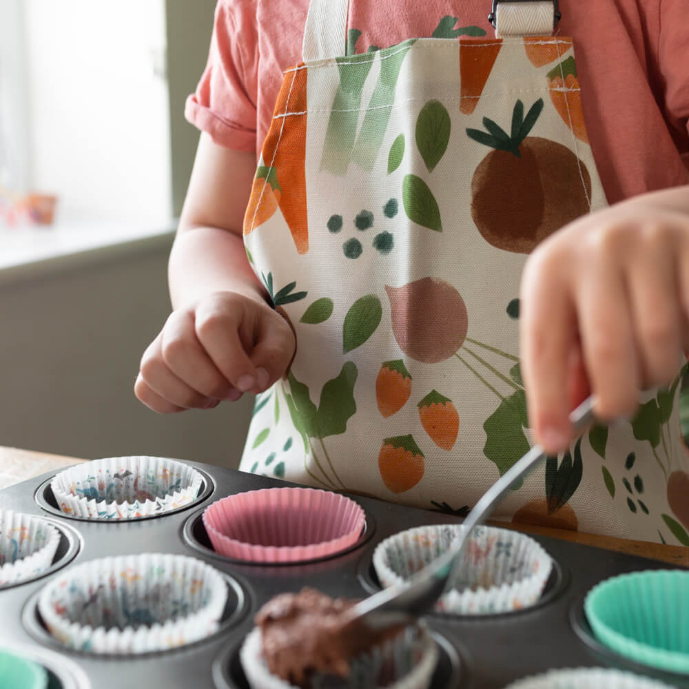 A child wearing an apron with vegetable print whilst baking